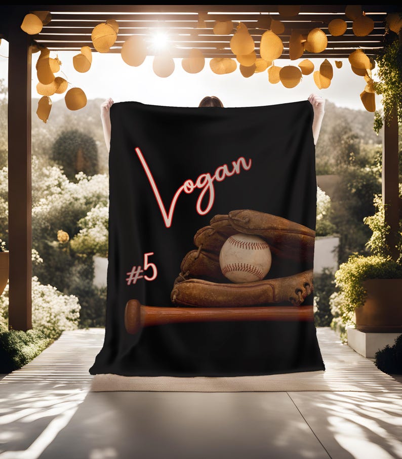 May include: Black fleece blanket with a red baseball glove, a baseball, and a wooden bat. The text "Logan #5" is printed in red on the blanket.