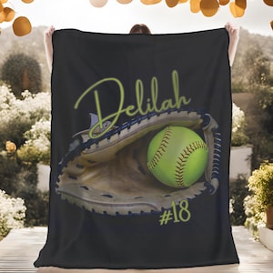 May include: Black fleece blanket with a green softball in a brown catcher's mitt. The text "Delilah #18" is printed in green on the blanket.