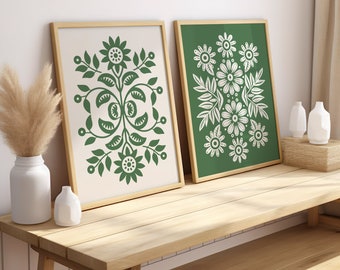 May include: Two framed prints with green backgrounds and white floral designs. The prints are hanging on a white wall above a wooden bench.