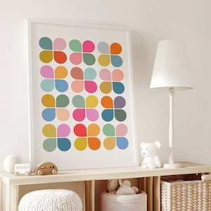 Puede incluir: Una impresión abstracta colorida con un patrón geométrico de círculos superpuestos en tonos de rosa, azul, verde, naranja y amarillo. La impresión está enmarcada en un marco blanco y está colgada en una pared blanca.