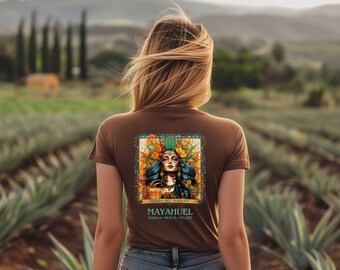 May include: Brown t-shirt with a graphic print of a woman with flowers in her hair and a glass of liquid. The text on the shirt reads "Diosa del Maguey" and "MAYAHUEL Tequila - Mezcal - Pulque".