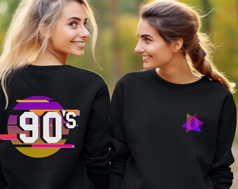 May include: Two women wearing black sweatshirts. One sweatshirt has a graphic of a circle with the text "90's" in a retro style. The other sweatshirt has a graphic of a purple star with the number "8" inside.