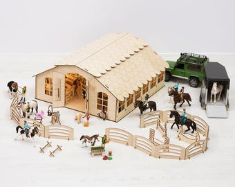 May include: A wooden toy horse stable with a brown roof and a green toy truck with a horse trailer. There are several miniature horses, riders, and fences.