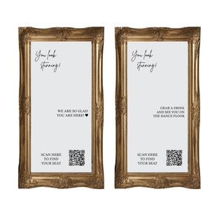 May include: Two rectangular mirrors with ornate gold frames. The left mirror displays the text: You look stunning! WE ARE SO GLAD YOU ARE HERE! SCAN HERE TO FIND YOUR SEAT with a QR code. The right mirror displays: You look stunning! GRAB A DRINK AND SEE YOU ON THE DANCE FLOOR SCAN HERE TO FIND YOUR SEAT with a QR code.