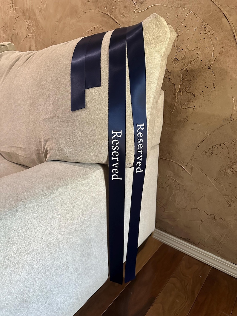 Peut inclure: Rubans de satin bleu marine avec le mot "Reserved" imprim&eacute; en blanc. Les rubans sont drap&eacute;s sur le dossier d'un canap&eacute; beige. Les rubans sont de couleur bleu fonc&eacute;.