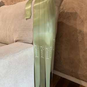 Peut inclure: Ruban de satin vert clair avec le mot "Reserved" imprim&eacute; en blanc. Le ruban est drap&eacute; sur un canap&eacute; beige. L'arri&egrave;re-plan est un mur brun textur&eacute;.