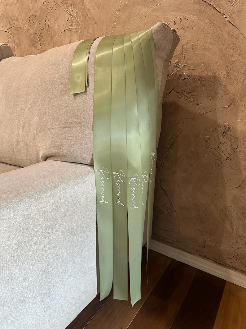 Peut inclure: Ruban de satin vert clair avec le mot "Reserved" imprim&eacute; en blanc. Le ruban est drap&eacute; sur un canap&eacute; beige. L'arri&egrave;re-plan est un mur brun textur&eacute;.