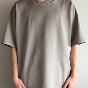 May include: A gray oversized t-shirt with short sleeves and a crew neck.