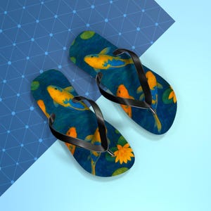 May include: A pair of flip-flops with a blue background featuring yellow and orange koi fish swimming among lily pads. The flip-flops have black straps and a blue and light blue background.