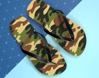 May include: A pair of camouflage-patterned flip-flops with black straps. The flip-flops feature a design in shades of green, brown, and tan. The background is a combination of blue and light blue, with a geometric pattern.