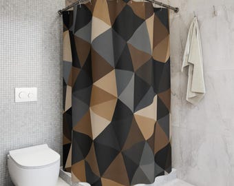 May include: A shower curtain featuring a geometric pattern of triangles in shades of dark brown, light brown, charcoal gray, and cream. The curtain hangs from a curved metal rod with visible rings, displaying a repeating angular mosaic design.