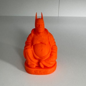 May include: Orange figurine of a smiling Buddha with a Batman-like cowl.