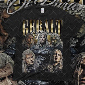 May include: Black t-shirt featuring a gold-colored text that reads "Geralt of Rivia." The shirt displays a collage of images of a man with long, white hair. The shirt is a Gildan brand.
