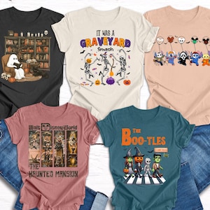 May include: Five Halloween-themed t-shirts with various graphic designs. One shirt features a ghost reading in a library, another says "It Was a Graveyard Smash," and a third has cartoon characters holding balloons. The other two shirts have "The Haunted Mansion" and "The Boo-tles" designs.