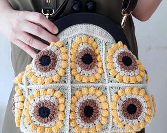 May include: A crocheted sunflower handbag with a brown leather strap and a black wooden frame.