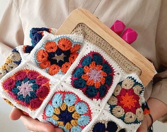 May include: A colorful crocheted bag with a wooden frame and pink clasps. The bag is made of granny squares in various colors, including red, orange, yellow, green, blue, and purple.