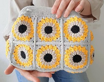 May include: A crocheted bag with a gray background and yellow and black sunflower designs.