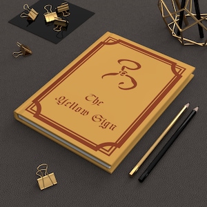 Libro sobrenatural lovecraftiano que representa el signo amarillo del rey en amarillo Misteriosa ficción espeluznante Terror cósmico Cuaderno de tapa dura Mate