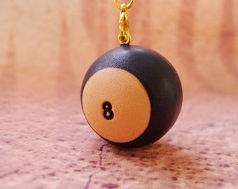 May include: A black and orange 8-ball keychain. The 8-ball is made of polymer clay and has a gold chain.
