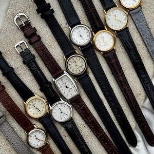 May include: A collection of ten analog wristwatches with leather straps in black, brown, and gray. The watches feature round or rectangular cases in gold or silver tones, white dials with Arabic or baton numerals, and metal buckles on the straps.
