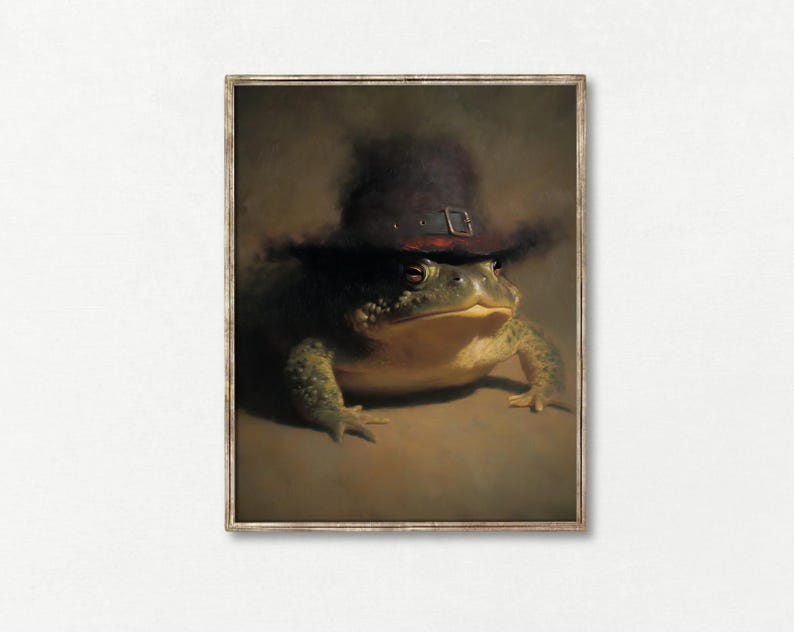 May include: A framed print depicting a frog wearing a dark hat with a buckle. The frog is rendered in detail with green and yellow skin. The artwork has a vintage, painterly style, set against a muted brown background.