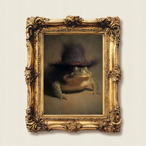 May include: A framed portrait of a frog wearing a dark hat with a buckle. The frog is green and brown, and the ornate gold frame adds a touch of elegance. The artwork has a vintage, whimsical feel.