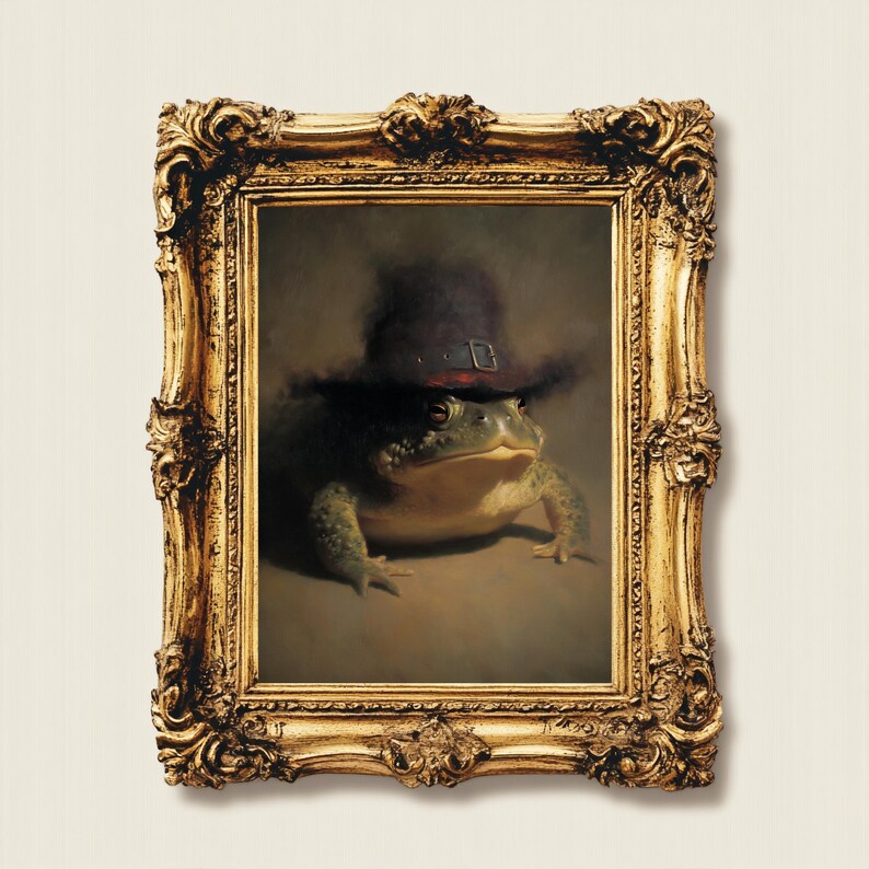 May include: A framed portrait of a frog wearing a dark hat with a buckle. The frog is green and brown, and the ornate gold frame adds a touch of elegance. The artwork has a vintage, whimsical feel.