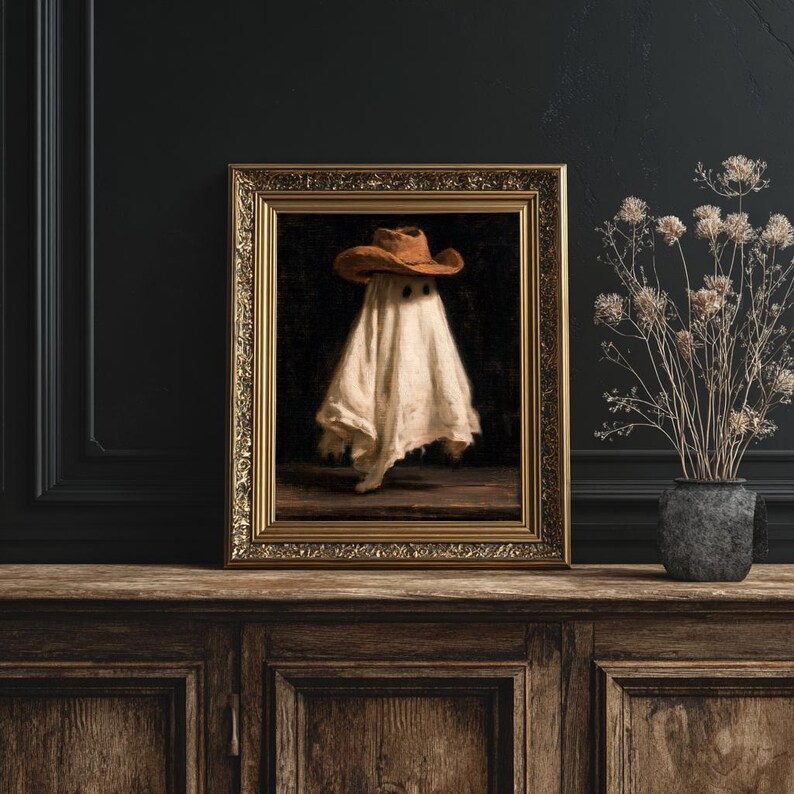 Pu&ograve; includere: Una stampa artistica incorniciata raffigurante un fantasma bianco che indossa un cappello da cowboy marrone su sfondo scuro. L'opera &egrave; racchiusa in una cornice dorata ornata, che mostra un soggetto centrale con due macchie oculari scure.