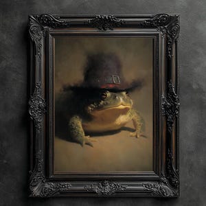 May include: A framed portrait of a large toad wearing a dark hat with a buckle. The toad is green and tan, set against a neutral background. The ornate black frame adds a classic touch to the artwork.