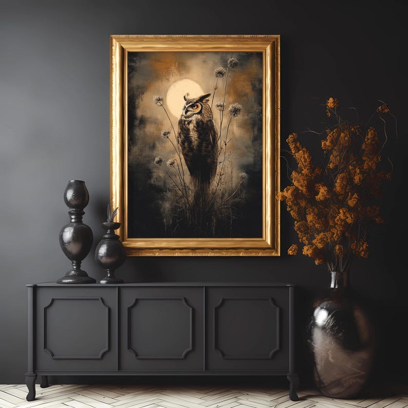 May include: A framed print of a brown and white owl perched on a branch with a full moon in the background. The owl is surrounded by tall grasses and flowers. The frame is gold and has a dark brown mat.