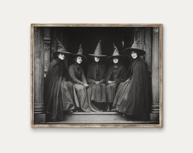 May include: A monochrome framed print shows five figures in cloaks and pointed hats, seated on steps. The vintage image has a mysterious quality, ideal for Halloween decorations. The image is reminiscent of a coven.