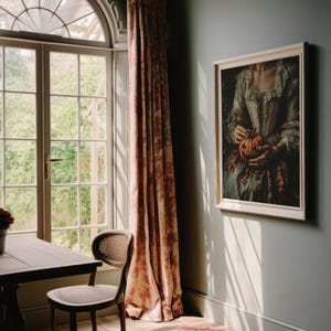K&ouml;nnte beinhalten: Ein gerahmtes Kunstwerk zeigt eine Person in historischem Kleid, die einen K&uuml;rbis h&auml;lt. Der Raum verf&uuml;gt &uuml;ber einen Holztisch, einen Korbstuhl und ein Fenster mit floralen Vorh&auml;ngen. Die W&auml;nde sind in einem ged&auml;mpften Gr&uuml;n gestrichen.