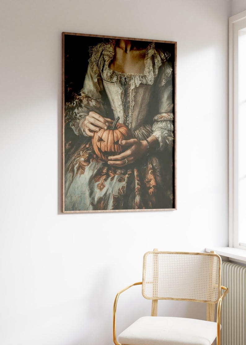 K&ouml;nnte beinhalten: Gerahmter Kunstdruck mit einem Vintage-Bild einer Person, die einen geschnitzten K&uuml;rbis h&auml;lt. Die Person tr&auml;gt ein historisches Kost&uuml;m mit wei&szlig;em Oberteil und gemustertem Rock. Der K&uuml;rbis hat ein geschnitztes Gesicht.