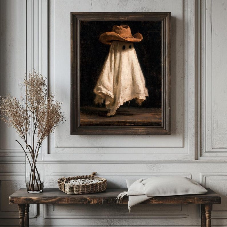 Pu&ograve; includere: Un dipinto a olio incorniciato raffigurante una figura spettrale avvolta in un lenzuolo bianco e che indossa un cappello da cowboy marrone. La figura &egrave; centrata su uno sfondo scuro, poggiata su una superficie in legno. La cornice &egrave; in legno scuro.