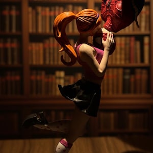 Peut inclure: Figurine d'une femme en haut rose et jupe noire embrassant une figurine de Spider-Man. La femme a les cheveux roux en queue de cheval et porte des chaussettes blanches &agrave; c&oelig;urs rouges. L'arri&egrave;re-plan est une biblioth&egrave;que.