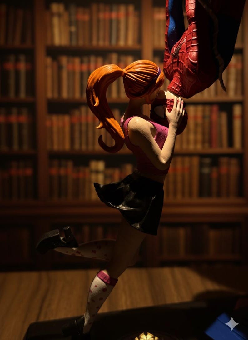 Peut inclure: Figurine d'une femme en haut rose et jupe noire embrassant une figurine de Spider-Man. La femme a les cheveux roux en queue de cheval et porte des chaussettes blanches &agrave; c&oelig;urs rouges. L'arri&egrave;re-plan est une biblioth&egrave;que.