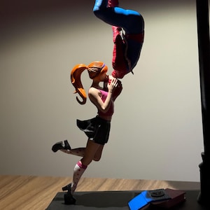 Peut inclure: Figurine repr&eacute;sentant Spider-Man embrassant une femme &agrave; l'envers. La femme porte un haut rose, une jupe noire et des chaussettes blanches &agrave; c&oelig;urs rouges. Spider-Man est dans son costume rouge et bleu classique. La base est noire.
