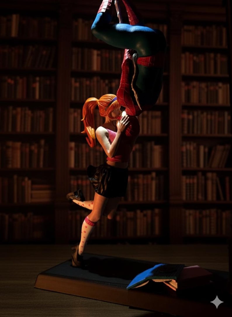 Peut inclure: Figurine repr&eacute;sentant une sc&egrave;ne de bande dessin&eacute;e. Une femme rousse en jupe noire embrasse une figurine en costume de Spider-Man, suspendue &agrave; l'envers. L'arri&egrave;re-plan est une biblioth&egrave;que avec des &eacute;tag&egrave;res remplies de livres.