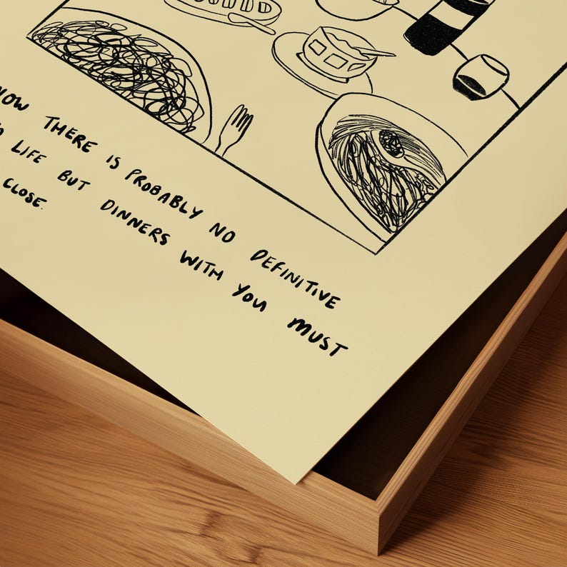 May include: A black and white line drawing of a meal, including pasta, soup, and a bottle of wine. The artwork is on a cream-colored paper and framed in a light brown wooden frame. Text on the paper reads: "NOW THERE IS PROBABLY NO DEFINITIVE TO LIFE BUT DINNERS WITH YOU MUST CLOSE."
