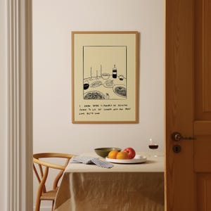 May include: A framed art print with a minimalist illustration of a dining table setting, including plates, wine glasses, and a bottle. The print has a light-colored background and a wooden frame. The text on the print reads: "I know there is probably no definitive purpose to life but dinners with your most came pretty close."