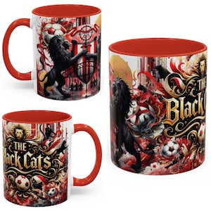 Può includere: Tazza in ceramica bianca con interno e manico rossi. La tazza presenta una grafica di leone nero, palloni da calcio e la scritta "The Black Cats" in oro. Il design include accenti rossi e dorati.