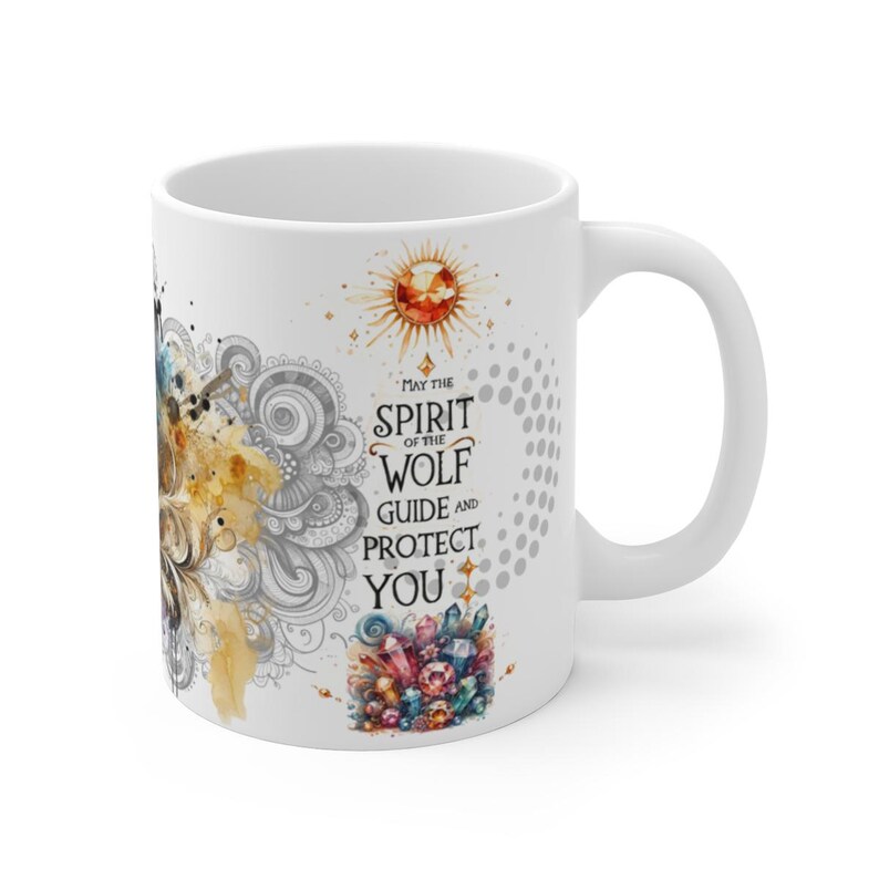 May include: White ceramic mug featuring a watercolor design with a wolf, sun, and crystals. The text reads "May the Spirit of the Wolf Guide and Protect You." The mug has a curved handle.