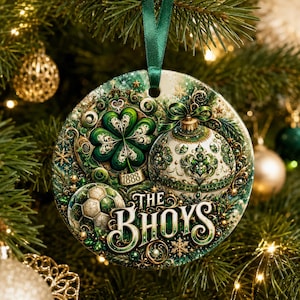 May include: A round ceramic Christmas ornament hanging from a green ribbon, featuring a four-leaf clover, a soccer ball, a decorative bauble, and the text "THE BHOYS" with the year "1888" in green, white, and gold tones with intricate filigree details.