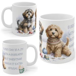 May include: A white ceramic mug featuring illustrations of two Cockapoo puppies in a snowy setting with Christmas ornaments. The text reads: Every day is a joy with a Cockapoo but Christmas makes it extra special. A small gingerbread man in a mug is included.