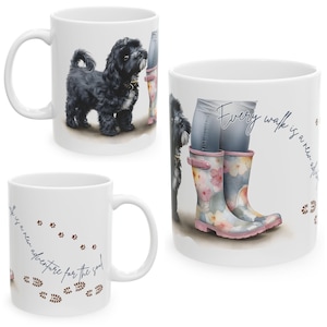 Può includere: Tazze in ceramica bianca con un design a cane e stivali da pioggia floreali. Una tazza presenta un cane nero, un'altra ha stivali floreali e il testo "Every walk is a new adventure for the soul."