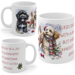May include: A white ceramic mug featuring a festive illustration of two Cockapoo dogs in the snow, wearing holiday scarves and hats. The text reads: Every day is a joy with a Cockapoo but Christmas makes it extra special, accented with holly.