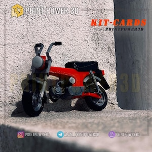 May include: A red and black miniature motorcycle model with the text "KIT-CARDS PRINTPOWER3D" on a white wall.