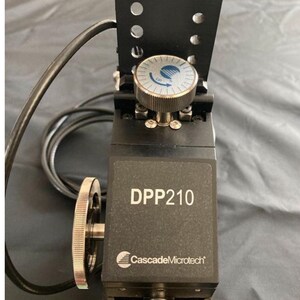 May include: A black and silver DPP210 micro-manipulator with a silver knob and a black control panel. The device has a label that reads "Cascade Microtech".