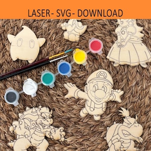Puede incluir: Figuras de madera cortadas con láser de personajes de videojuegos, como Mario y la Princesa Peach, dispuestas con botes de pintura y pinceles. Las figuras no están pintadas y están listas para personalizar. El texto "LASER- SVG- DOWNLOAD" es visible.