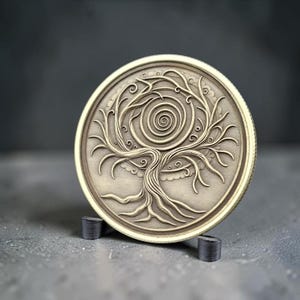 Peut inclure: Un médaillon circulaire en métal de couleur laiton présentant un relief d'un arbre avec des branches et des racines étendues. Le centre de la canopée de l'arbre contient un motif en spirale proéminent. Le médaillon est maintenu par un support noir.